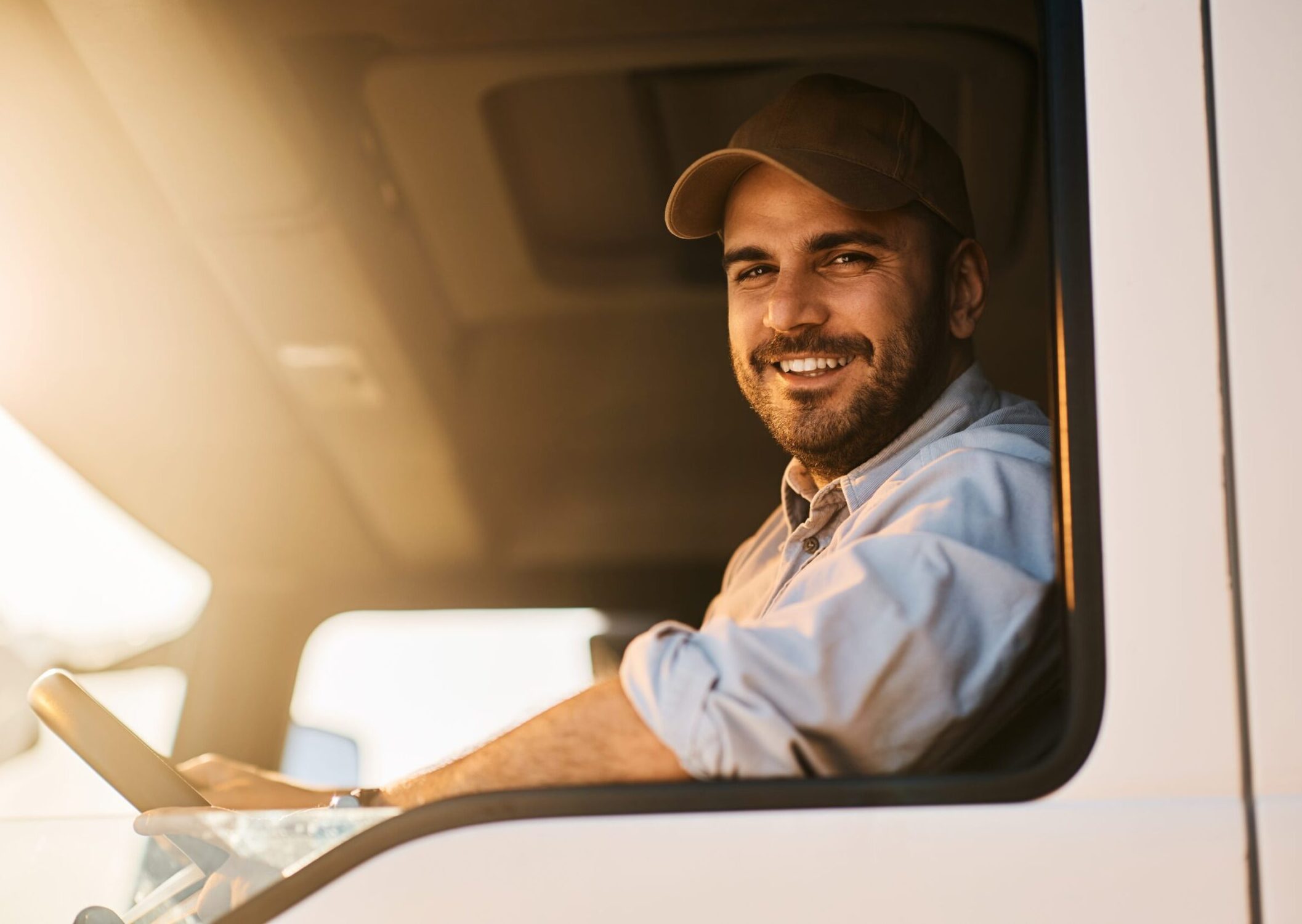 Happy,Truck,Driver,Sitting,In,Vehicle,Cabin,And,Looking,At